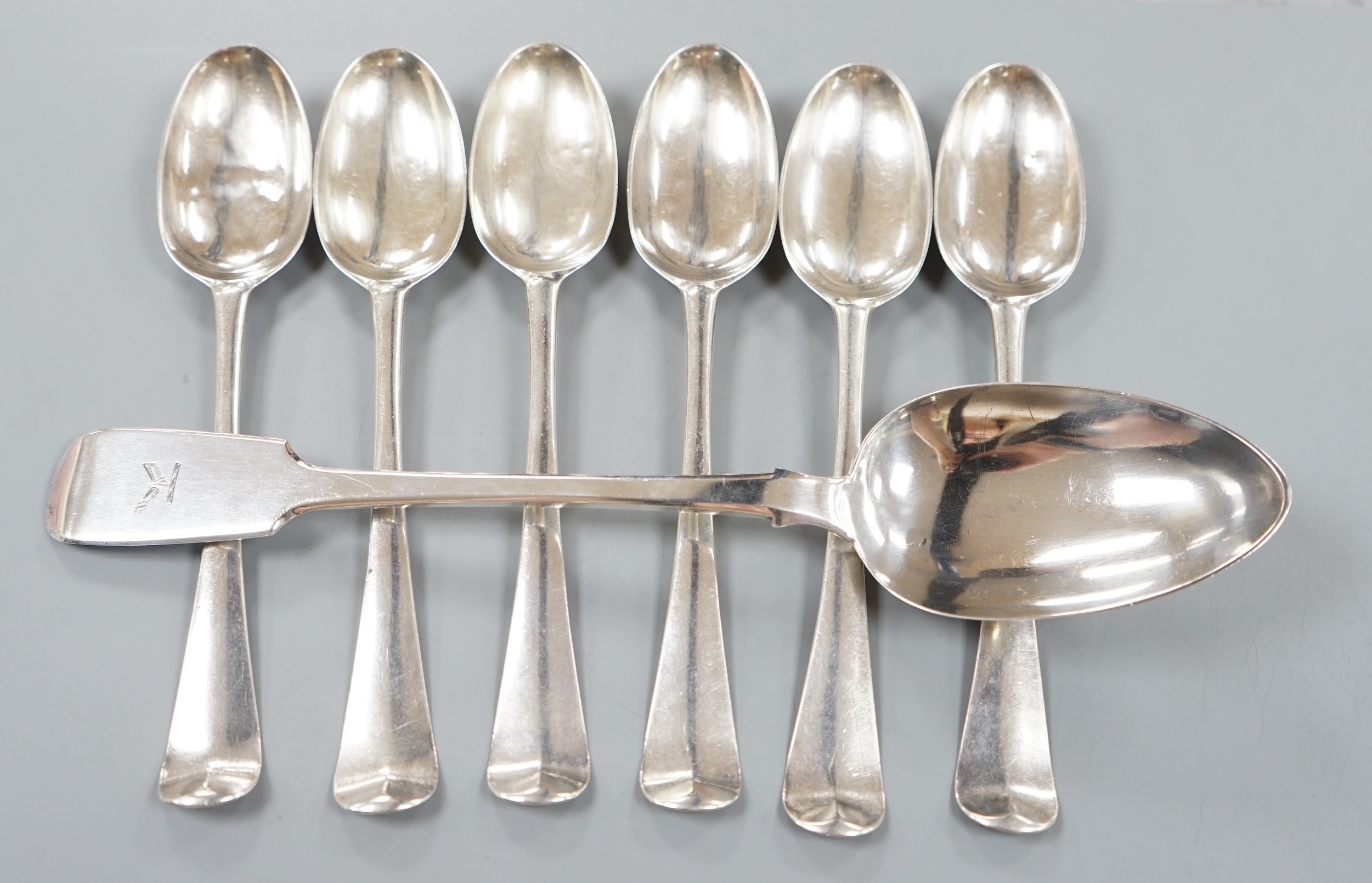 A set of six early George III Irish silver Hanovarian pattern table spoons, with engraved crests, Daniel Popkins, Dublin, 1761, 22.5cm and a later Irish silver fiddle pattern basting spoon, Dublin, 1877, 20oz.